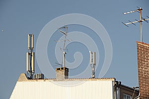 Many antennas on the roof of an urban house