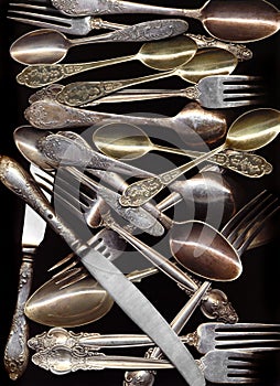 Many antique spoons, knives, forks on black background