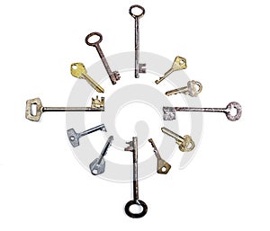 Many assorted old multi-colored metal antique keys of different shapes laid out in circle isolated on white background. Home