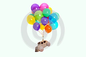 Many balloons tied to wooden toy car flying on white background