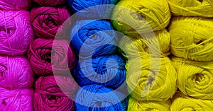 Many balls of wool placed in columns of the same color. There are pink, purple, blue and yellow