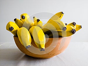 Many bananas in bowl on table viewed from side