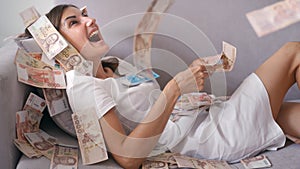 Many banknotes fly in the air overhead in slow motion. A girl lies and a lot of money falls on her. happy woman rejoices