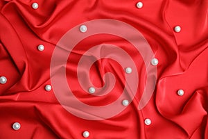 Many beautiful pearls on delicate red silk, top view