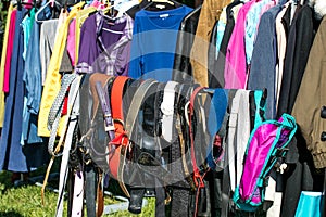 Many belts and adult clothing on rack at garage sale