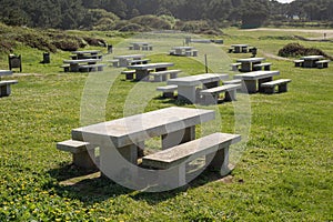 Many benchs and stone tables in a park
