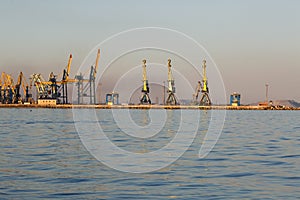 Many big cranes silhouette in the sea port of Azov at golden light of sunset. Mariupol