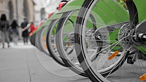Many bikes for rent on the streets of Paris. Close-up rear wheel. Against the background go unrecognized people. The