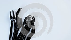 Many black plastic disposable forks spin on a white background.