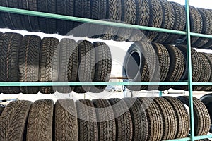 Many black rubber car tires on store shelf for sale