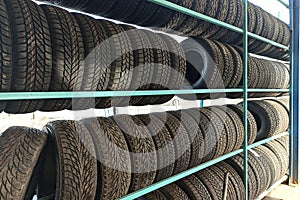 Many black rubber car tires on store shelf for sale