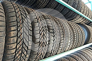 Many black rubber car tires on store shelf for sale