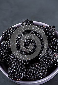 Many blackberries in a plate on a black background Stacked image Still life photography