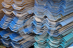 Many blue house roof tiles are stacked in an industrial factory.