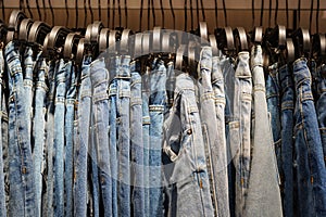 Many blue jeans hang on a rack. shopping, selling