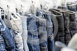 Many blue jeans on hangers for sale in street market in Thailand, close up