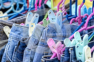 Many blue jeans on hangers for sale in street market in Thailand, close up