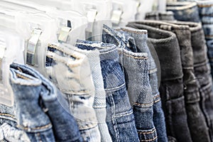 Many blue jeans on hangers for sale in street market in Thailand, close up