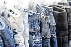 Many blue jeans on hangers for sale in street market in Thailand, close up