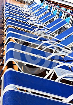 Many blue sunbeds on the deck of ship.