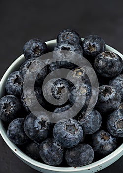 Many blueberries background in a plate on a black background Stacked image Still life photography