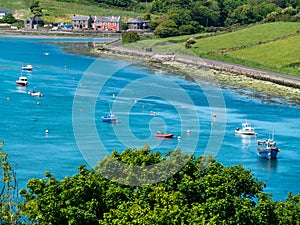 Many boats are anchored in Clonakilty Bay on a sunny spring day. Seascape of the south of Ireland. Blue sea water