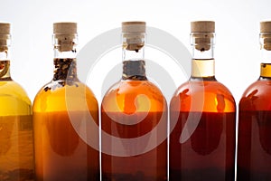 Many bottles with brown transparent alcoholic drink. Homemade tinctures based on natural herbs. Liquor and traditional