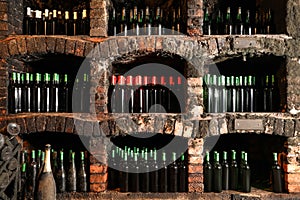 Many bottles of different alcohol drinks on shelves in cellar