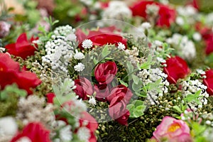 Many bouquets of red roses decorated with other white flowers and green leaves. View from above.
