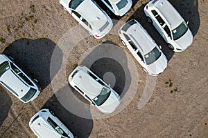 Many brand new cars covered in protective foil on sale parked outside on dealer parking lot