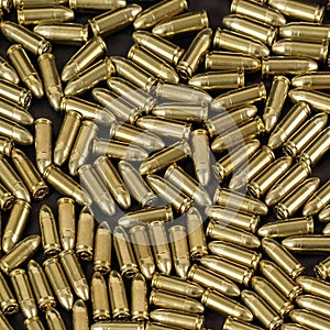 Many brass gun bullets on black table closeup view from above
