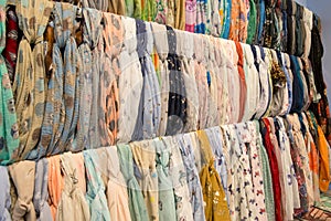 Many bright female scarfs and shawl. colorful scarves hanging in the market. clothes rack with a selection of scarves or scarfs.