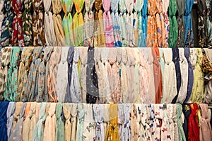 Many bright female scarfs and shawl. colorful scarves hanging in the market. clothes rack with a selection of scarves or scarfs.