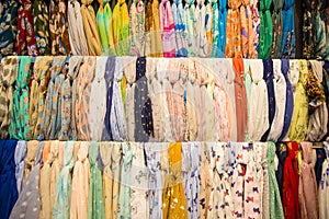 Many bright female scarfs and shawl. colorful scarves hanging in the market. clothes rack with a selection of scarves or scarfs.