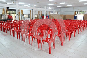 Many bright red plastic chairs arranged in a white floor in the meeting room