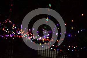 Many brightly blurred multicolored garland lights on a black background