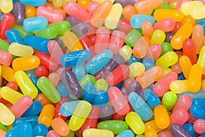 Close up on many brightly colored jelly bean like candies in pastel colors