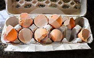 Broken egg shells from eggs used for cooking in paper mache egg carton on marble countertop