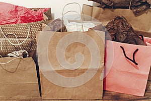 Many brown paper bags with presents on background of white wall.
