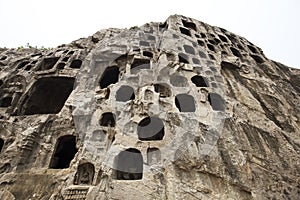 Many buddhist statues are carved into a rock cave