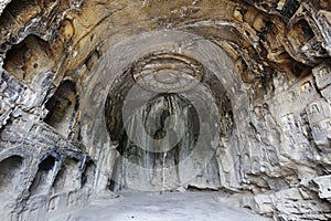 Many buddhist statues are carved into a rock cave