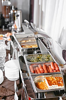 Many buffet heated trays ready for service. Breakfast in hotel catering buffet, metal containers with warm meals