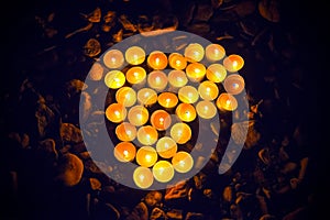 Many burning heart-shaped candles on stony ground