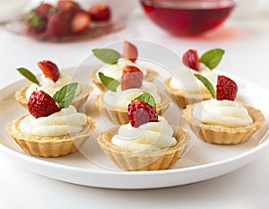 Many cakes, cupcakes with fresh fruits (strawberries), whipped cream, jelly and mints