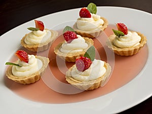 Many cakes, cupcakes with fresh fruits (strawberries), whipped cream, jelly and mints