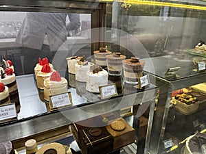 Many cakes in pastry shop glass display in a bakery for sale.