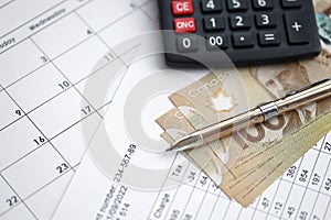 Many calculation results in schedules lies on table with canadian money bills, calculator and pen