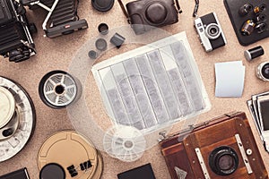 Many cameras roll of films, contacts on wooden cork table. Photographer workspace. Flat lay. View from above.