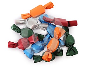 Many candies in colorful wrappers on white background, top view