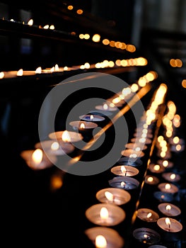 Many candle flames glowing in the dark, create a spiritual atmosphere.